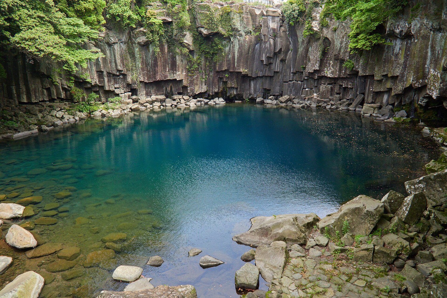 濟州島天帝淵瀑布的碧綠水潭與柱狀節理岩壁