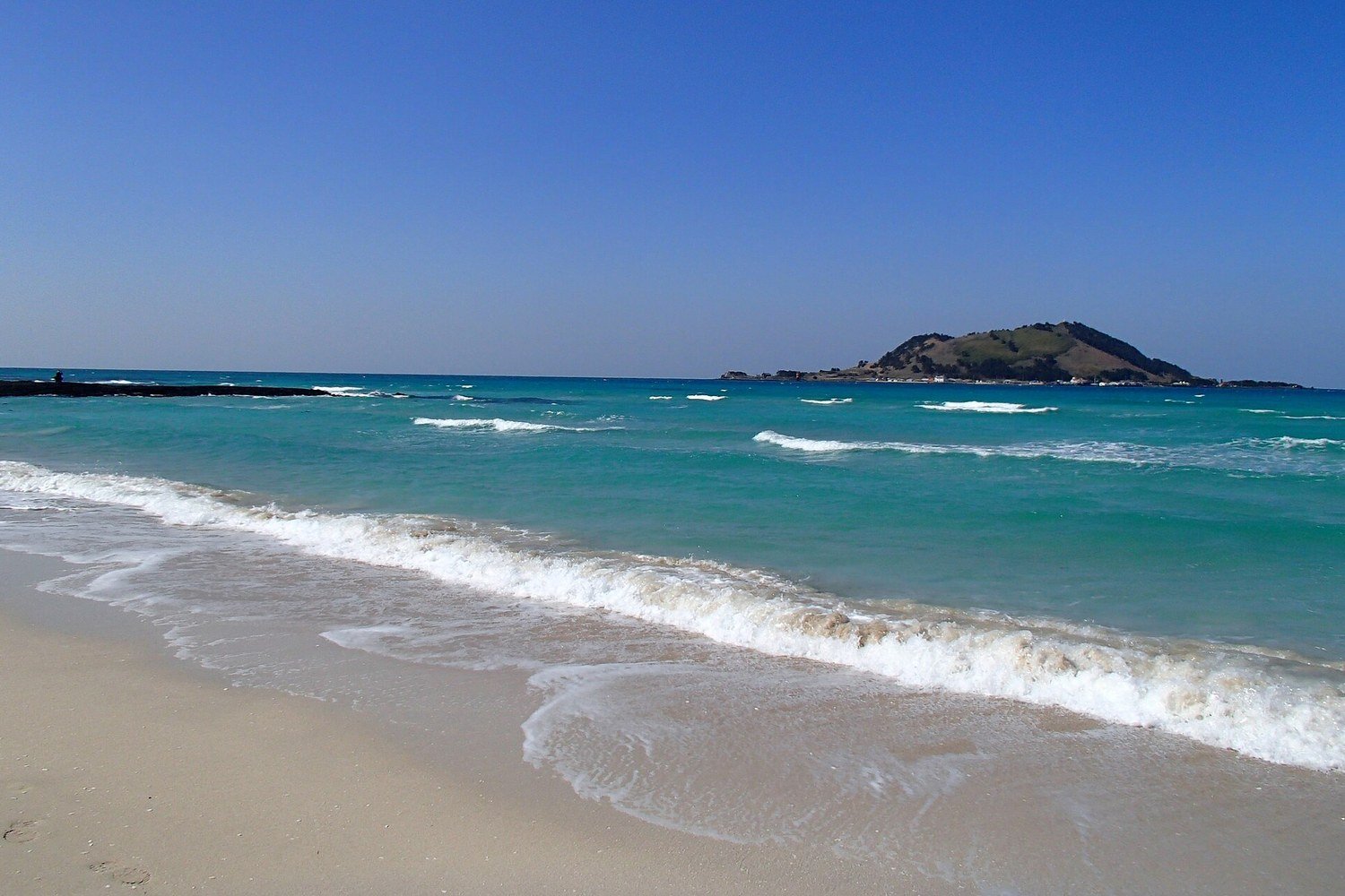 濟州島協才海灘的白沙與翡翠色海水，遠處是飛揚島