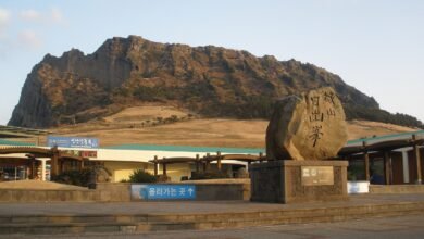 濟州島城山日出峰與入口的石碑，背景是海邊突起的火山口