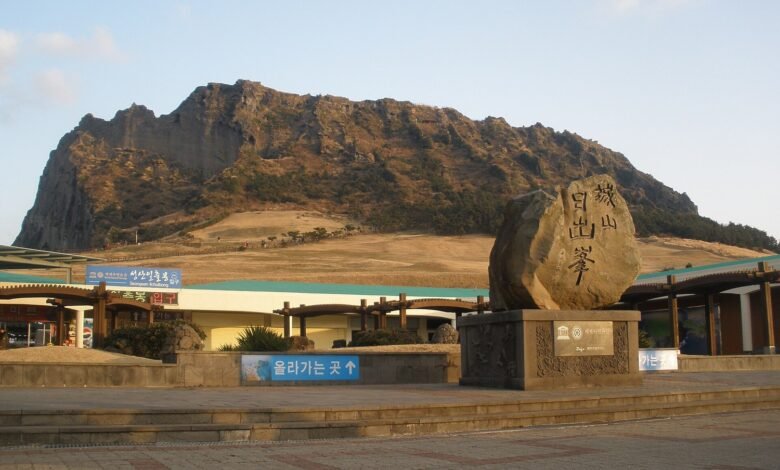 濟州島城山日出峰與入口的石碑，背景是海邊突起的火山口